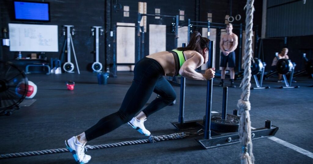 Sportlerin beim Sled Push im Functional-Fitness-Training, einer zentralen Kraftstation im HYROX Rennen.