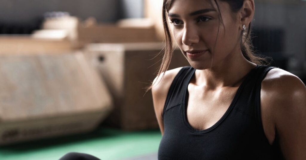 Fokussierte Frau im Pilates-Studio vor einer intensiven Reformer Pilates Einheit für Kraft und Stabilität.